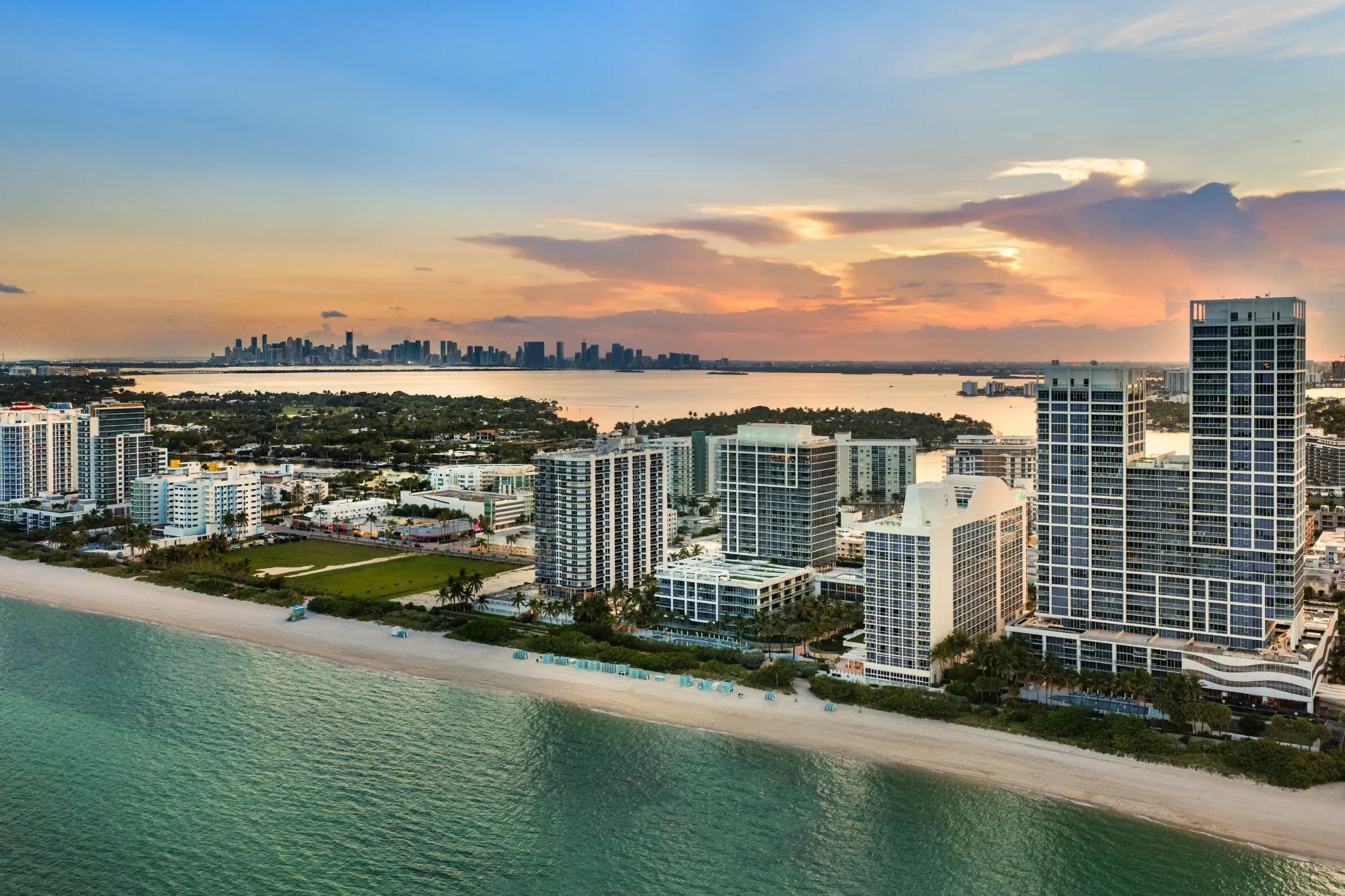Aerial view of Miami Beach at dusk with the Carillon towers and the Miami skyline beyond
