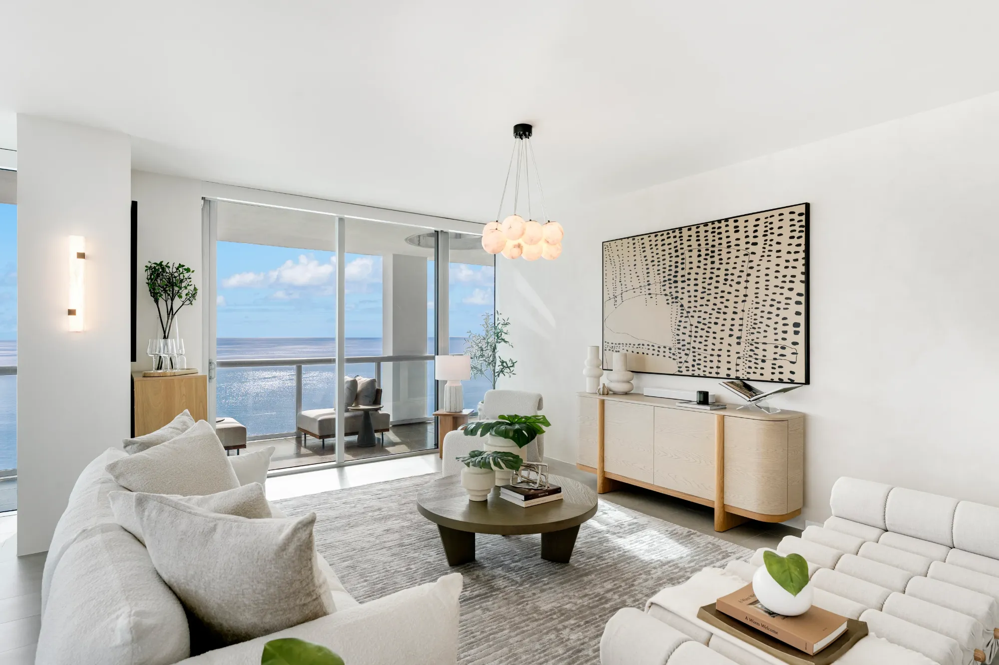 Living room in white with floor-to-ceiling glass and the ocean beyond